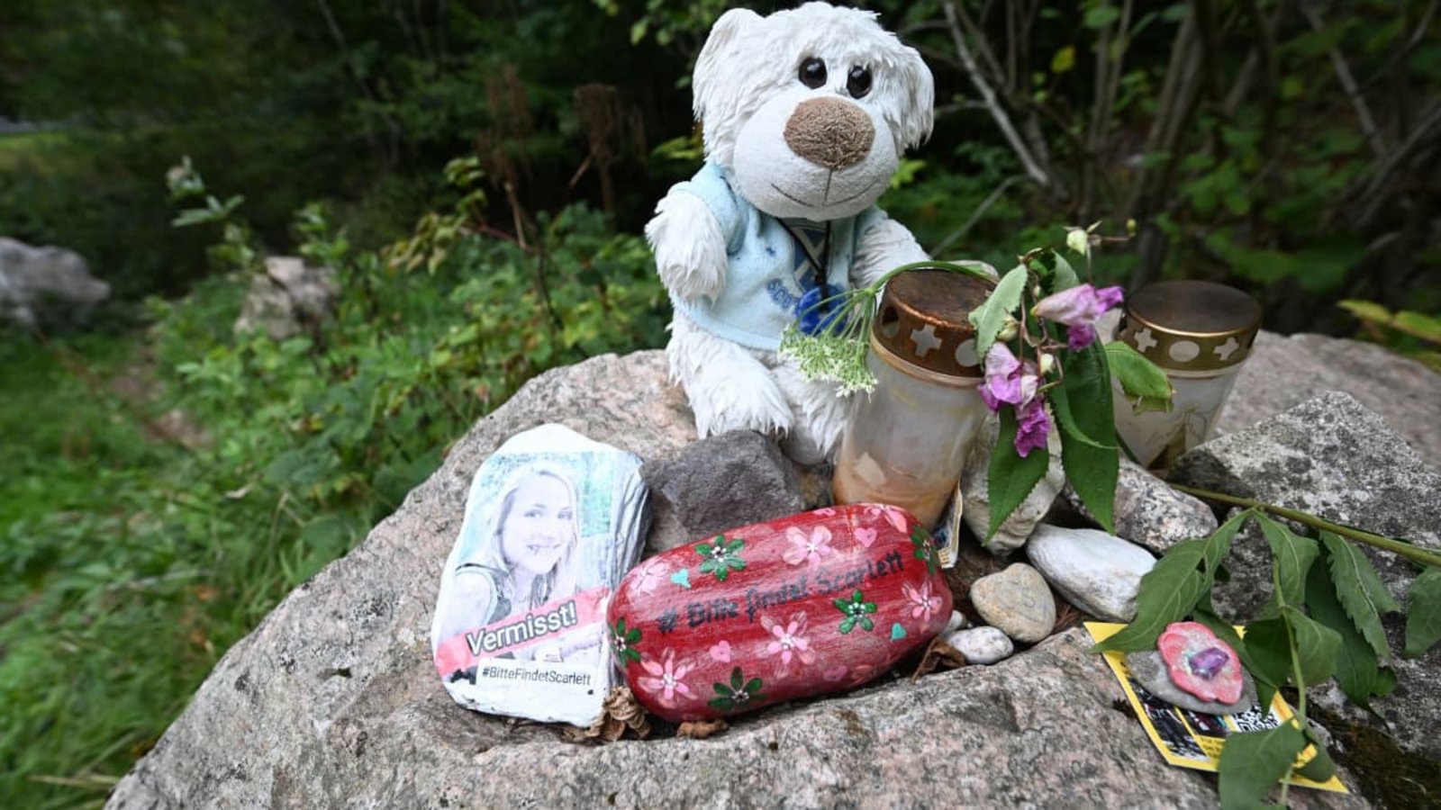 An einem Stein an einem Wanderparkplatz am Schluchtensteig liegen Blumen, ein Kuscheltier, ein bemalter Stein mit der Aufschrift "Vermisst" und einem Foto.Bernd Weißbrod/dpa