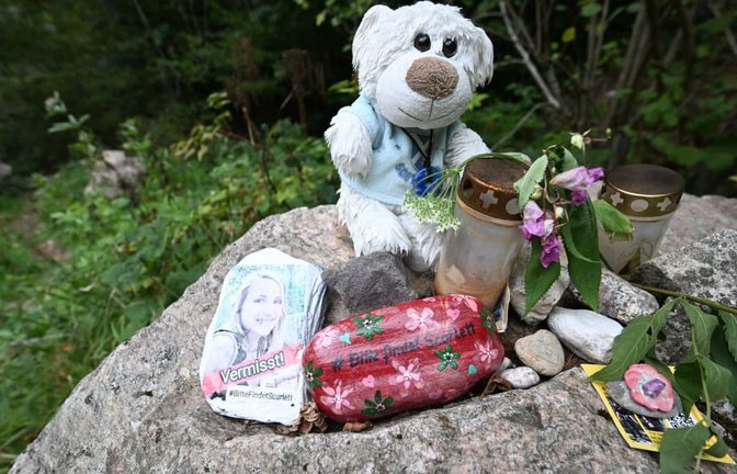 An einem Stein an einem Wanderparkplatz am Schluchtensteig liegen Blumen, ein Kuscheltier, ein bemalter Stein mit der Aufschrift "Vermisst" und einem Foto.<span class='image-autor'>Bernd Weißbrod/dpa</span>
