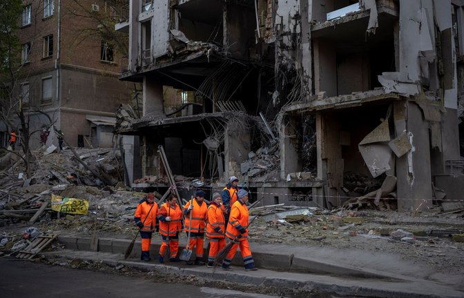 Arbeiter eines Aufräumtrupps agieren vor einem Gebäude nach einer Explosion in Kiew: Die führenden westlichen Industrienationen (G7) beraten über milliardenschwere Zuschüsse für die Ukraine.<span class='image-autor'>Foto: Emilio Morenatti/AP/dpa</span>