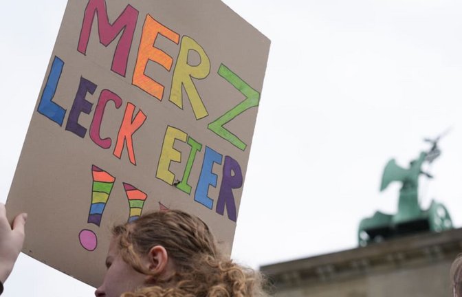 ARCHIV - 08.05.2026, Berlin: Eine Teilnehmerin einer Demonstration gegen die Wehrpflicht hält ein Plakat, auf dem steht „Merz leck Eier“. Online wurde später daraus „Mehrzweckeier“.<span class='image-autor'>Sven Kaeuler/dpa +++ dpa-Bildfunk +++</span>