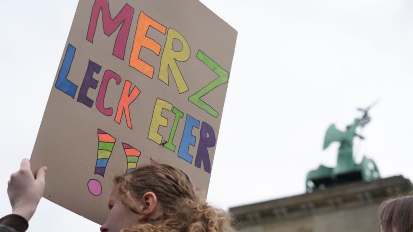 ARCHIV - 08.05.2026, Berlin: Eine Teilnehmerin einer Demonstration gegen die Wehrpflicht hält ein Plakat, auf dem steht „Merz leck Eier“. Online wurde später daraus „Mehrzweckeier“.Sven Kaeuler/dpa +++ dpa-Bildfunk +++ ARCHIV - 08.05.2026, Berlin: Eine Teilnehmerin einer Demonstration gegen die Wehrpflicht hält ein Plakat, auf dem steht „Merz leck Eier“. Online wurde später daraus „Mehrzweckeier“.Sven Kaeuler/dpa +++ dpa-Bildfunk +++