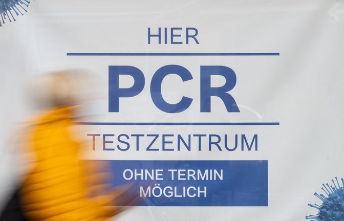 Eine Passantin geht in Stuttgart an einem Transparent, das auf ein Testzentrum hinweist, vorbei.<span class='image-autor'>Foto: dpa/Marijan Murat</span>