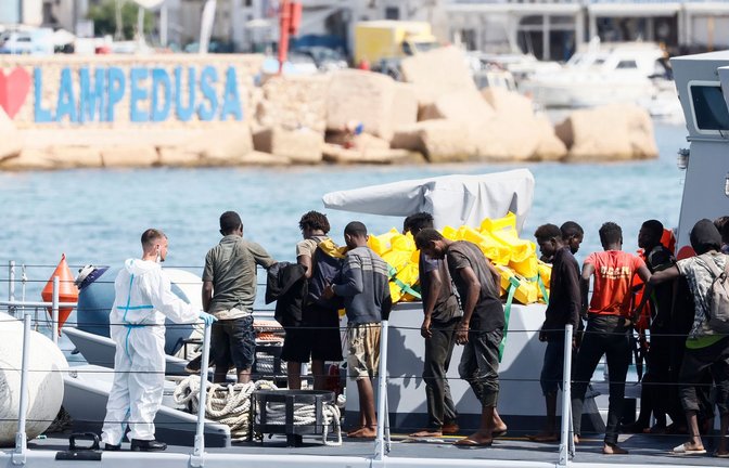 Gerettete Migranten stehen auf einem Boot der italienischen Finanzpolizei, bevor sie im Hafen der sizilianischen Insel Lampedusa von Bord gehen.<span class='image-autor'>Foto: Cecilia Fabiano/LaPresse/AP/dpa</span>