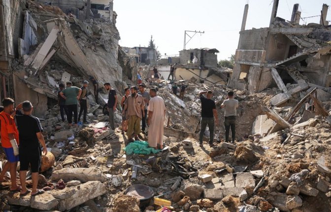 Palästinenser begutachten am Ort eines israelischen Luftangriffs im Flüchtlingslager al-Maghazi zerstörte Gebäude. (Archivbild)<span class='image-autor'>Abdel Kareem Hana/AP/dpa</span>