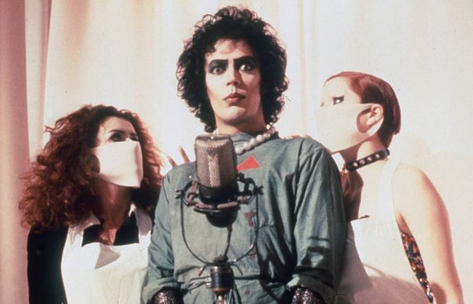 Tim Curry - mit Patricia Quinn (li.) und Nell Campbell (re.) als Frank N. Furter in dem Kultfilm „Rocky Horror Picture Show“ (1975)<span class='image-autor'>imago images/United Archives</span>