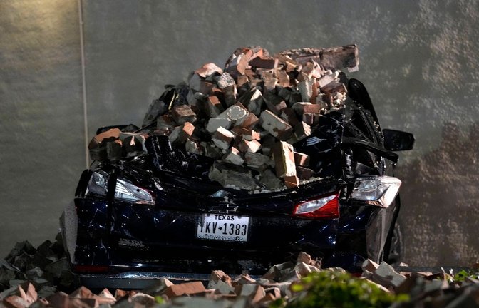 Ein Auto, das von herabfallenden Ziegeln einer umgestürzten Hauswand zerquetscht wurde, steht auf einem Parkplatz in der Innenstadt von Houston.<span class='image-autor'>Foto: David J. Phillip/AP/dpa</span>