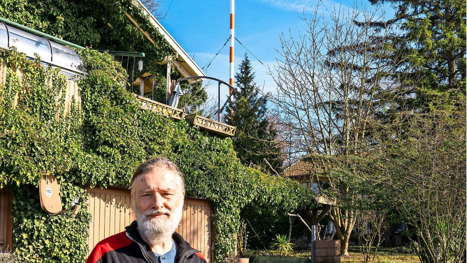 Jürgen Fegert vor seinem Holzhäuschen und dem 273 Meter hohen Sendemasten – fast 40 Jahre lebt er hier.Foto: Maren Recken Jürgen Fegert vor seinem Holzhäuschen und dem 273 Meter hohen Sendemasten – fast 40 Jahre lebt er hier.Foto: Maren Recken