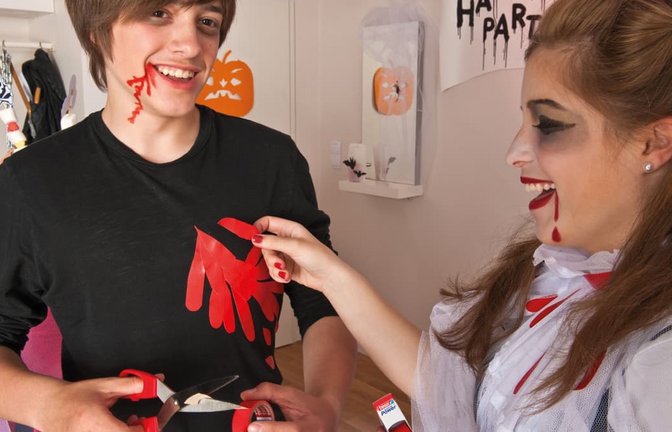 Zwei Kinder verkleiden sich für Halloween: Rotes Gewebeband imitiert Blut: Ausgeschnittene Tropfen und Streifen lassen sich auf ein ausgedientes schwarzes Shirt kleben.<span class='image-autor'>Tesa/DIY Academy/dpa-tmn/dpa</span>