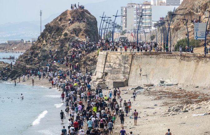 Menschen laufen am Strand entlang, nachdem sie versucht hatten, von der marokkanischen Stadt Fnideq im Norden in die spanische Exklave Ceuta zu gelangen (red).<span class='image-autor'>STR/AP/dpa</span>