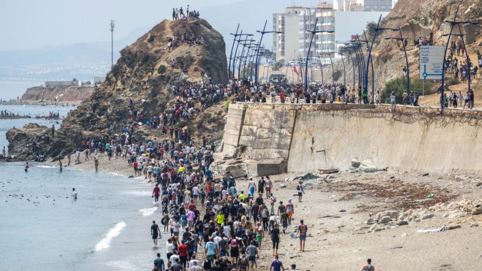 Menschen laufen am Strand entlang, nachdem sie versucht hatten, von der marokkanischen Stadt Fnideq im Norden in die spanische Exklave Ceuta zu gelangen (red).STR/AP/dpa Menschen laufen am Strand entlang, nachdem sie versucht hatten, von der marokkanischen Stadt Fnideq im Norden in die spanische Exklave Ceuta zu gelangen (red).STR/AP/dpa