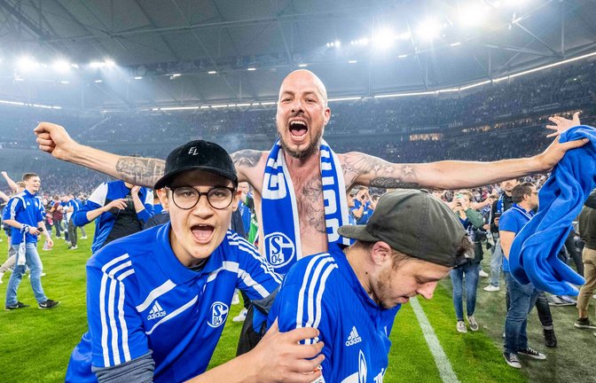 Schalker Fans haben den Rasen gestürmt und bejubeln den Aufstieg.<span class='image-autor'>Foto: David Inderlied/dpa</span>