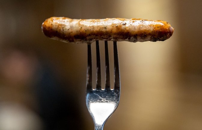 Eine Nürnberger Bratwurst steckt auf einer Gabel.<span class='image-autor'>Foto: dpa/Daniel Karmann</span>