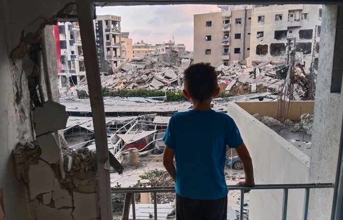 Ein Junge blickt aus einem beschädigten Raum des Jabal Amel Krankenhauses auf ein zerstörtes Gebäude, das bei einem israelischen Luftangriff in der südlichen Hafenstadt Tyrus getroffen wurde.<span class='image-autor'>Foto: Uncredited/AP/dpa</span>