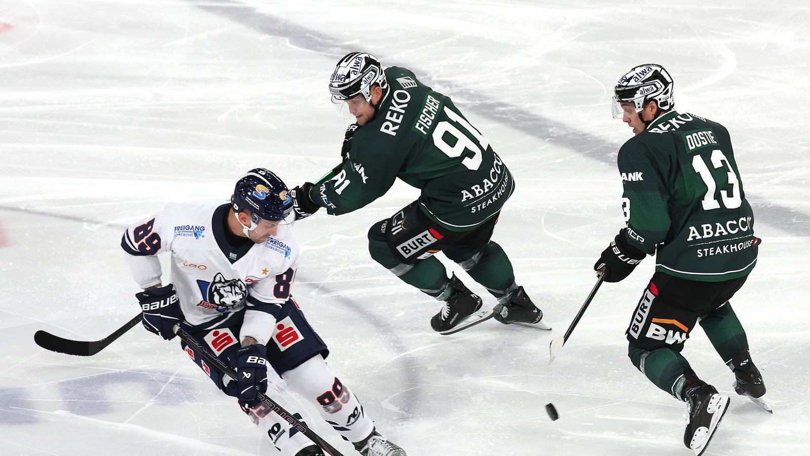 Alex Dostie (von rechts) und Mike Fischer versuchen, den Kasseler Hans Detsch von der Scheibe zu trennen. Foto: Baumann