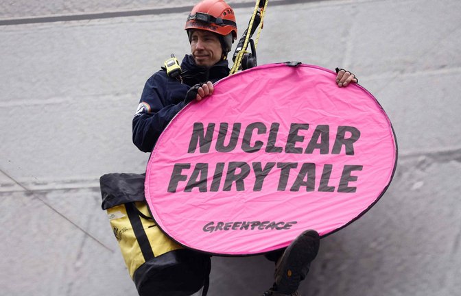 Ein Umweltaktivist von Greenpeace seilt sich vom Dach des Expo-Gebäudes in Brüssel ab und verzögert den Beginn des „Atomgipfels“.<span class='image-autor'>Foto: AFP/KENZO TRIBOUILLARD</span>