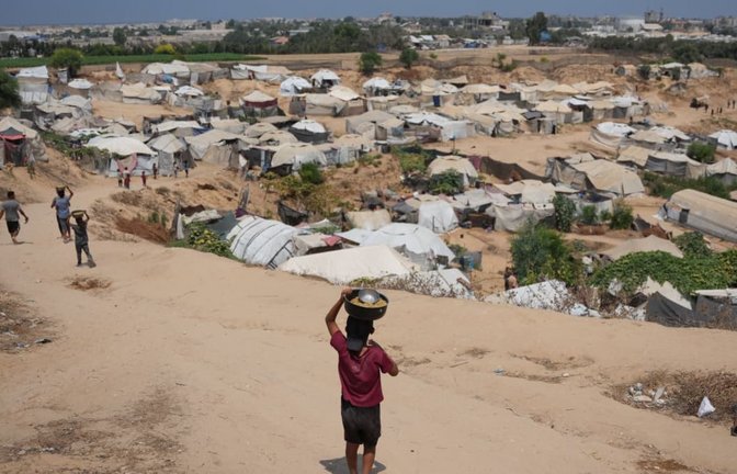 Vertriebene palästinensische Kinder tragen im zentralen Gazastreifen Essensrationen.<span class='image-autor'>Abdel Kareem Hana/AP/dpa</span>