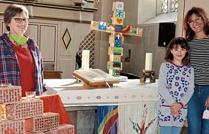 Elke Gratz (zwischen „Klagemauer“ und Altar) hatte die zündende Idee für das Corona-Kreuz. Barbara Manz und ihre Tochter Charlotte waren maßgeblich an der Umsetzung des außergewöhnlichen Projekts beteiligt. Foto: Gergen