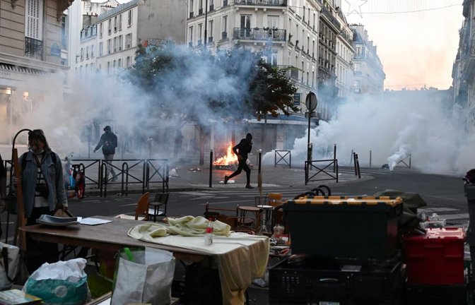 Ein Demonstrant rennt durch Tränengas, während es auf einem Flohmarkt erneut Zusammenstöße zwischen Demonstranten und Polizeibeamten in Paris dibt.<span class='image-autor'>Emma Da Silva/AP/dpa</span>