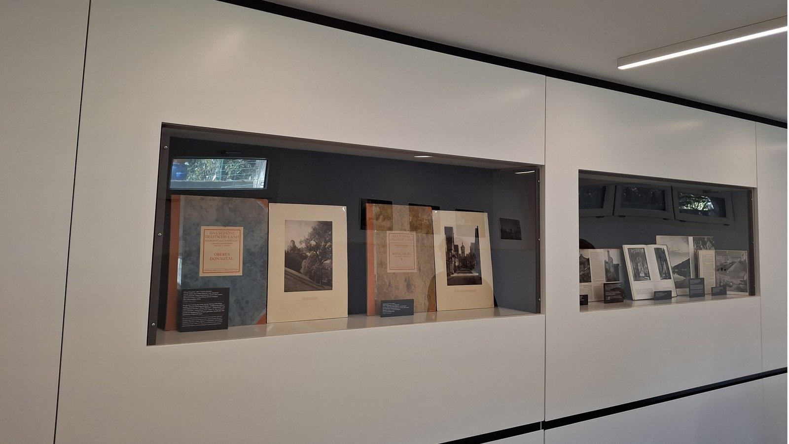 Blick in den  Ausstellungsraum. In den Vitrinen sind Zeugnisse von Otto Lossens Fotoarbeiten, darunter Landschaften und Stadtporträts aus Württemberg, die auch von touristischen Stellen verwendet wurden. Nicht immer wurde der Name Otto Lossen genannt. Bilder aus Fotoserien wie „Bilder aus Schwaben auf Hauff-Platten“ sind auch Teil der Schau.Foto: Golombek