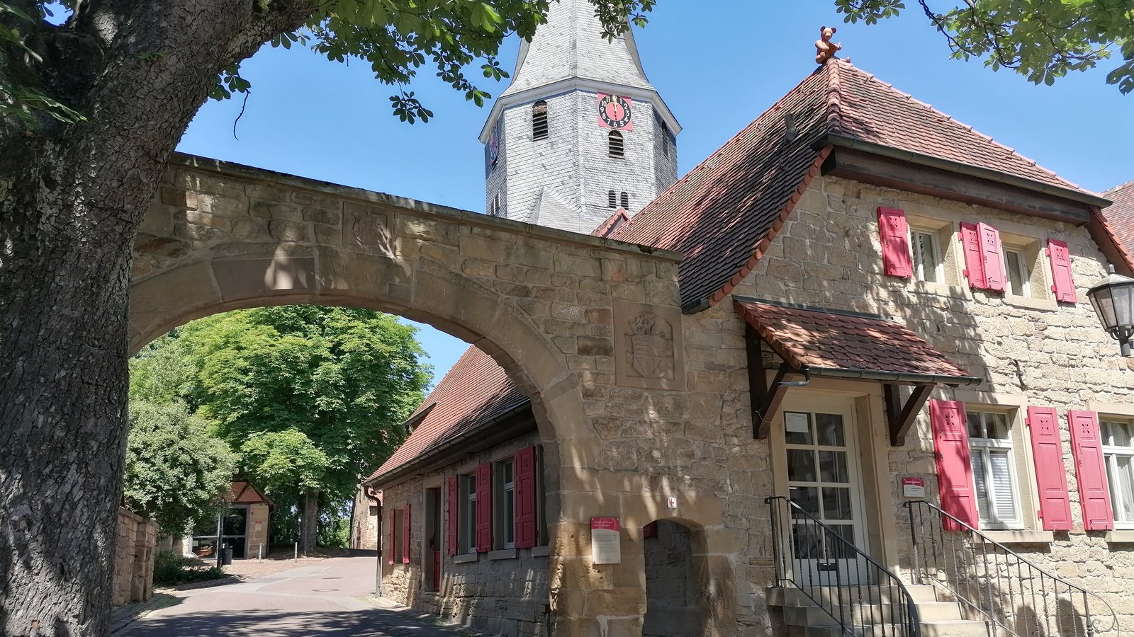 Das Torwächterhaus mit dem Torbogen und dahinter der Glockenturm bilden den Eingangsbereich zum Amthof der gesuchten Kommune.  Fotos: Banholzer