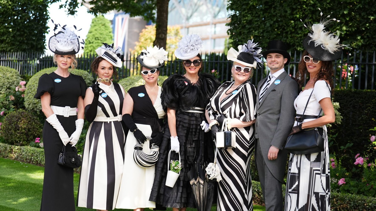 Die Gruppe setzt bei Royal Ascot auf ein konsequentes Schwarz-Weiß-Thema: gestreifte Kleider, elegante Handschuhe, Zylinder und auffällige Hüte mit Federn, Blüten und grafischen Formen ergeben einen abgestimmten, sehr klassischen Auftritt.Foto: picture alliance/dpa/PA Wire | Mike Egerton