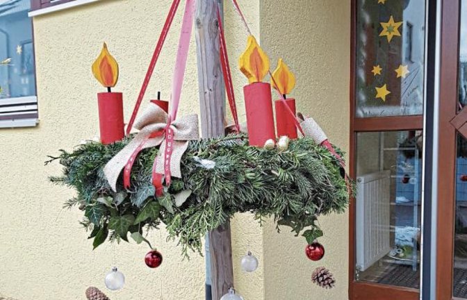 Die Kinder und Erzieherinnen des evangelischen Kindergartens Villa Sonnenschein in Kleinsachsenheim wünschen ein frohes Weihnachtsfest und senden einen Gruß vom Kindergarteneingang. An dem großen Adventskranz wird immer eine Holzkerze mehr aufgesteckt. Foto: Selinger