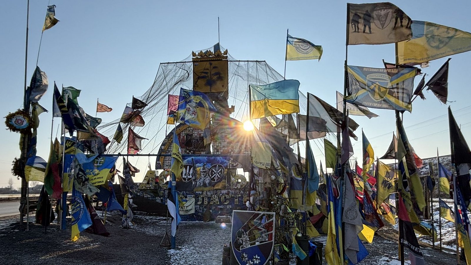 Gedenkstelle für gefallene Kameraden: An der Kreuzung beim Dörfchen Kamjanka haben Soldaten der seit mehr als sieben Monate dauernden Schlacht um Pokrovsk ukrainische Flahnen und die ihrer Verbände aufgestellt. Mit einem Netz schützen sie die Gedenkstelle vor russischen Drohnenangriffen.Foto: Franz Feyder