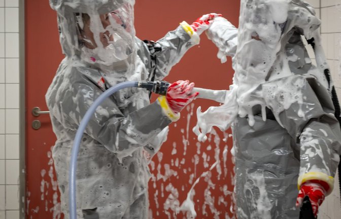 Louise Götze (l) und Ursula Pfitzner, Intensivpflegerinnen und Koordinatorinnen auf der Sonderisolierstation der Charité, desinfizieren sich während eines Pressetermins nach der Rückkehr aus dem Patientenzimmer in der Schleuse mit einer Schaumlösung.<span class='image-autor'>Foto: Soeren Stache/dpa</span>