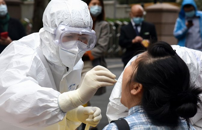 Archivbild aus dem Jahr 2020: Ein Mitarbeiter des Gesundheitswesens im Schutzanzug entnimmt einer Frau in Qingdao eine Abstrichprobe für den COVID-19-Test.<span class='image-autor'>Foto: dpa/Li Ziheng</span>