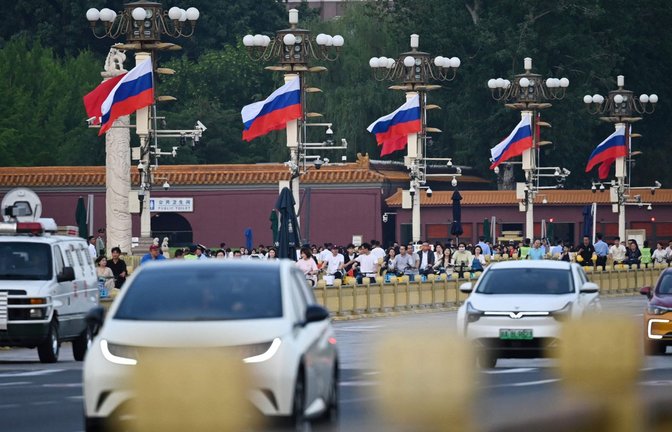 Am Tiananmen Platz rollt der Verkehr an russischen Fahnen vorbei.<span class='image-autor'>Foto: GREG BAKER/AFP</span>
