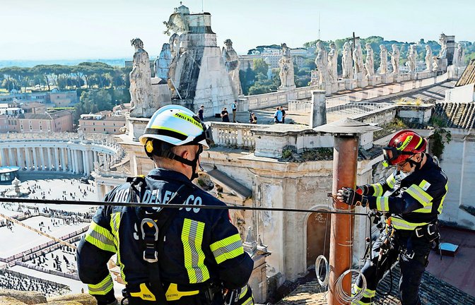 Ein Bauarbeiter installiert auf dem Dach der Sixtinischen Kapelle im Vatikan den Schornstein, durch den von Mittwoch an schwarzer oder weißer Rauch aufsteigen und vom Erfolg der Konklave-Wahlgänge künden wird.<span class='image-autor'>Foto: Vatican media/dpa</span>