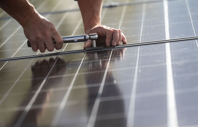 Ein Arbeiter montiert Photovoltaikmodule auf dem Dach eines Wohnhauses. Das Comeback der Solarbranche in Deutschland lockt Investoren an.<span class='image-autor'>Foto: Marijan Murat/dpa</span>