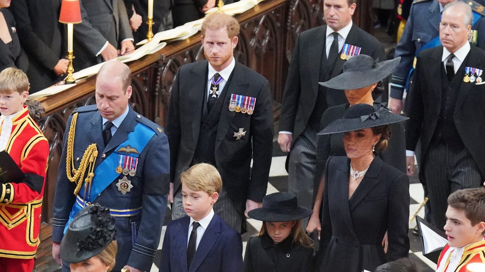 2022 stirbt Queen Elizabeth II. Prinz William (vorne l-r), Prinz von Wales, und sein Sohn Prinz George, seine Tochter Prinzessin Charlotte, und seine Frau Kate, Prinzessin von Wales, und dahinter Prinz Harry, Herzog von Sussex, und seine Frau Meghan, Herzogin von Sussex, kommen zum Staatsakt vor der Beisetzung von Königin Elizabeth II. in der Westminster Abbey.Foto: picture alliance/dpa/PA Wire | Dominic Lipinski