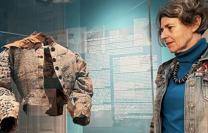 Ingrid von Beyme vom Museumsteam präsentiert das Jäckchen von Agnes Richter.<span class='image-autor'>Foto: Eberhard Reuß</span>