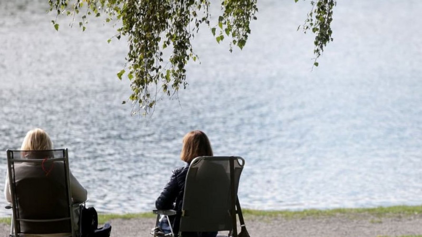 Zwei Frauen sitzen auf Klappstühlen an einem See in der Sonne. (Symbolbild)Thomas Warnack/dpa Zwei Frauen sitzen auf Klappstühlen an einem See in der Sonne. (Symbolbild)Thomas Warnack/dpa