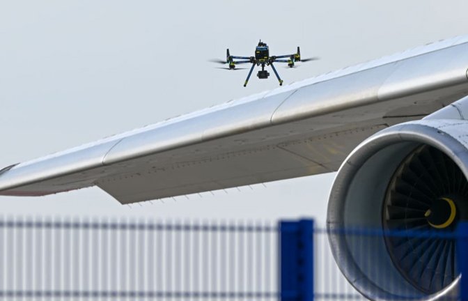 Eine Drohne der Polizei ist über einer Flugzeugtragfläche zu sehen.<span class='image-autor'>Hendrik Schmidt/dpa</span>