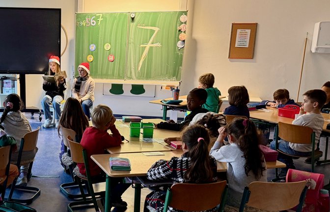 Die Klasse 6b der Ferdinand-Steinbeis-Realschule und ihre Klassenlehrerin Ute Heinrichs möchten in der Vorweihnachtszeit Freude verschenken. Deshalb lesen die Sechstklässler zwei Mal in der Woche in die ersten Klassen der Schlossbergschule vor. Die ersten Klassen sind seit diesem Jahr im Gebäude der FSR untergebracht. Kontakt besteht aber kaum, da die Erstklässler im Anbau sind und einen eigenen Eingang benutzen. Nun wollte die 6b die „Kleinen“ im Schulgebäude einfach mal willkommen heißen und ihnen mit Geschichten eine Freude bereiten. Jetzt war es soweit: Zwei Sechstklässlerinnen zogen mit dem goldenen Geschichtenbuch und zwei Weihnachtsmützen auf dem Kopf in Richtung 1d. Mit großen Augen und voller Konzentration lauschten die Kleinen den zwei Großen, als sie ihre Vorweihnachtsgeschichte – zuvor fleißig geübt – vorlasen. Immer dienstags und freitags werden nun zwei Sechstklässler in die ersten Klassen gehen.  <span class='image-autor'>Foto: p</span>
