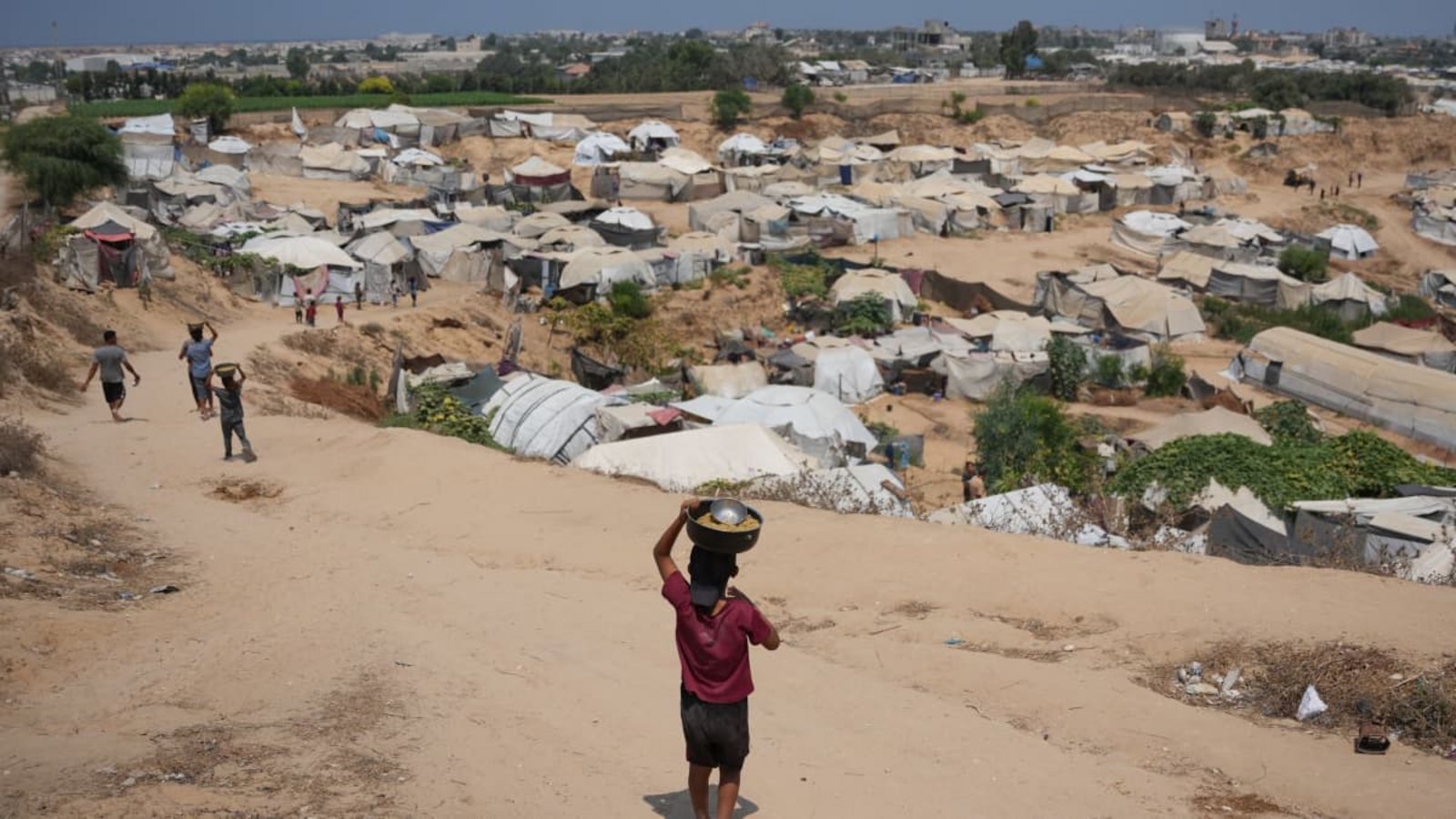 Vertriebene palästinensische Kinder tragen im zentralen Gazastreifen Essensrationen in ihre Notunterkünfte. Der Wiederaufbau soll erst nach der Entwaffnung der Hamas beginnen.Abdel Kareem Hana/AP/dpa Vertriebene palästinensische Kinder tragen im zentralen Gazastreifen Essensrationen in ihre Notunterkünfte. Der Wiederaufbau soll erst nach der Entwaffnung der Hamas beginnen.Abdel Kareem Hana/AP/dpa