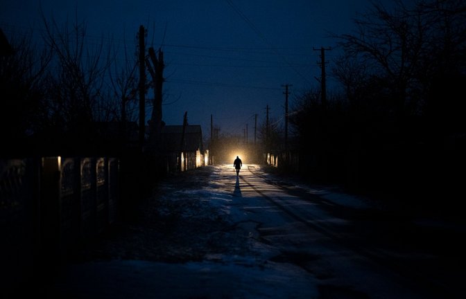 Ein Mann ist während eines Stromausfalls in Kolytschiwka im Scheinwerferlicht eines Autos zu sehen.<span class='image-autor'>Foto: Daniel Cole/AP/dpa</span>