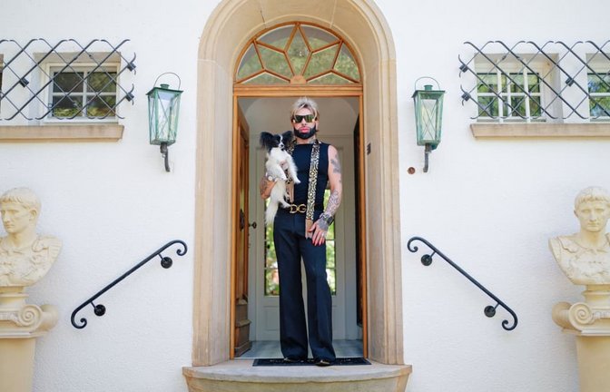Harald Glööckler mit Hund Ikarus in der Eingangstür seines „Château Pompöös“ in Kirchheim an der Weinstraße.<span class='image-autor'>Uwe Anspach/dpa</span>