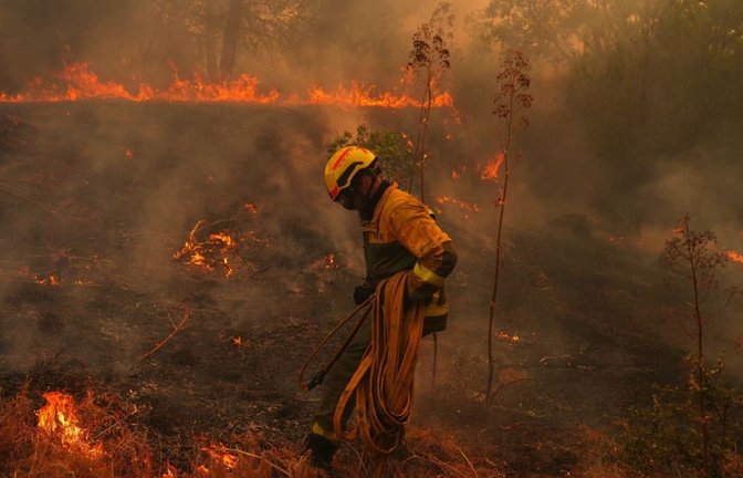 San Martín de Valdeiglesias: Ein Feuerwehrmann trägt einen Schlauch, während er einen Waldbrand bekämpft. Spanien kämpft gegen zahlreiche Waldbrände. Wegen der schweren Feuer rief die Regierung für die Umgebung der Hauptstadt Madrid sowie für die Region Ávila den Notstand aus.<span class='image-autor'>Manu Fernandez/AP/dpa</span>