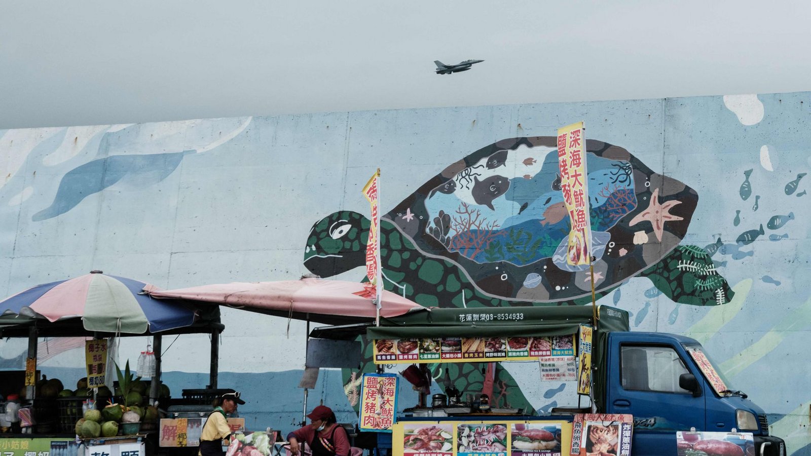 Streetfood und Streitkräfte: Eine Straßenszene in Hualien, einer Stadt im Osten Taiwans. Im Hintergrund hebt ein taiwanesischer F-16-Kampfjet von einer Militärbasis ab.Foto: AFP/Yasuyoshi Chiba