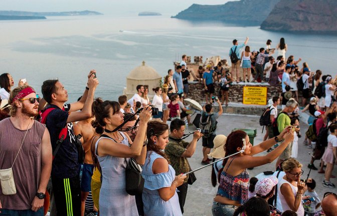 Touristen fotografieren  den Sonnenuntergang nahe Oia auf Santorin:  Übertourismus  – ein bekanntes Bild.<span class='image-autor'>Foto: dpa/Angelos Tzortzinis</span>
