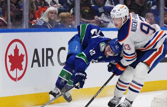 Quinn Hughes von den Vancouver Canucks wird von Ryan Nugent-Hopkins von den Edmonton Oilers zu Fall gebracht.<span class='image-autor'>Foto: Darryl Dyck/The Canadian Press via AP/dpa</span>
