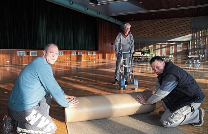 Zuerst wird der Teppich ausgerollt: Torsten Linzner, Karl Grausam und Sebastian Zaiß (von links) haben gestern in aller Frühe mit den Aufbauarbeiten für die Gewerbeschau in der Illinger Stromberghalle begonnen.  Foto: Banholzer