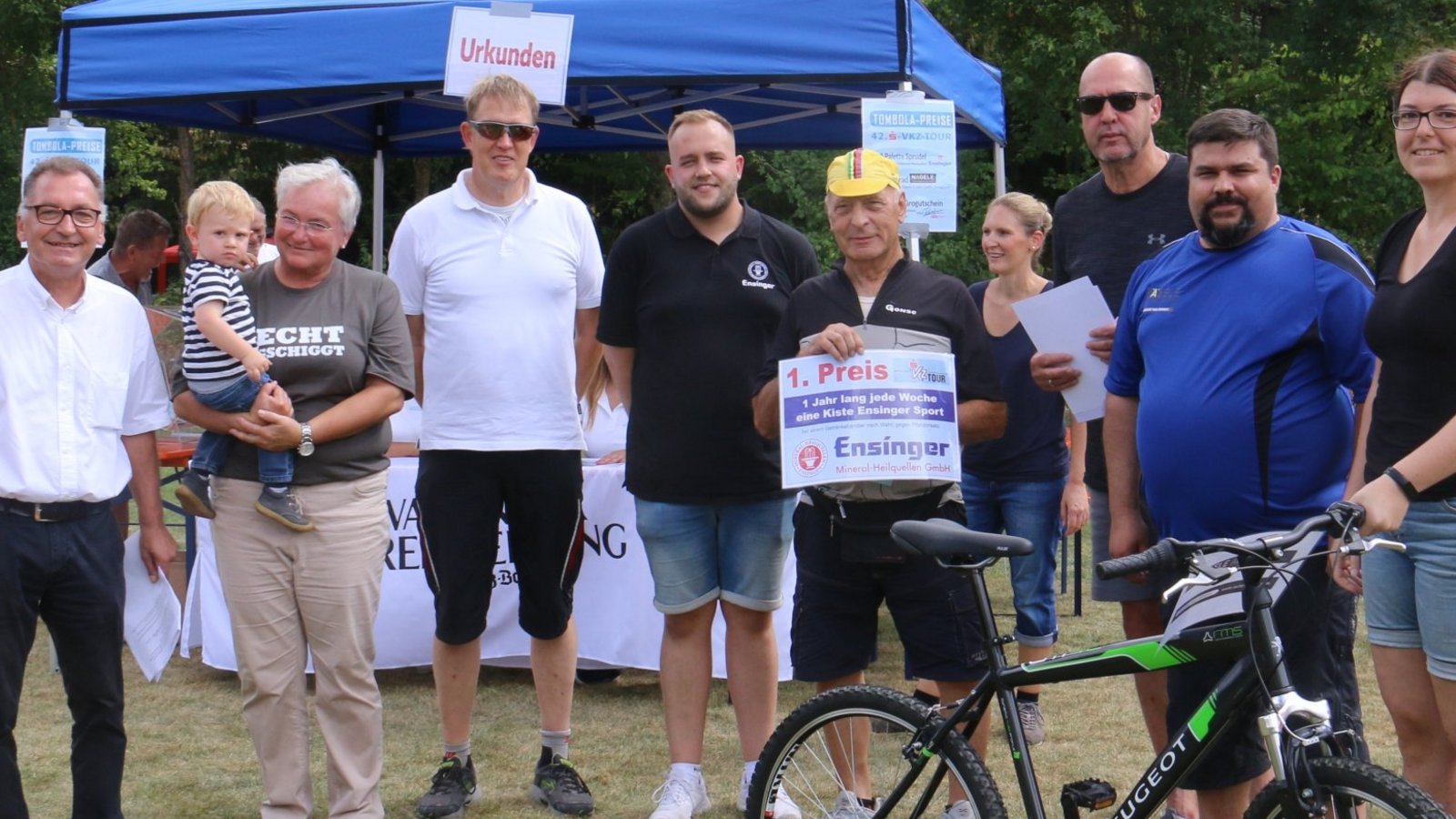 Übergabe der Tombola-Preise (von links, vorne): VKZ-Verkaufsleiter Volker Blessing; „Glücksfee“ Anton auf dem Arm von Anita Braig, KSK-Filialdirektorin Vaihingen; Hartmut Villinger, VKZ-Geschäftsführer; Nico Kütterer von Ensinger Mineral-Heilquellen; Gewinner Heinz Berner aus Nussdorf; Frank Schöbinger für Gewinner Erich Dorn aus Kleinglattbach; Joaquim Ribeiro vom Autohaus Nägele und Verena Hecht für Gewinner Alexander Hecht aus Vaihingen.