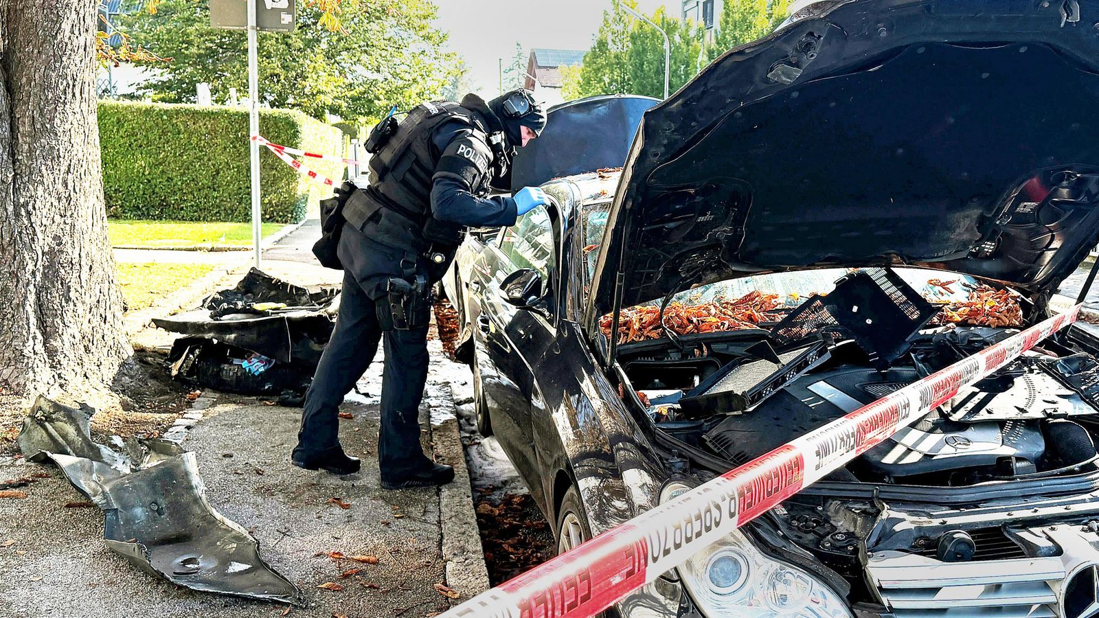 Ein Polizist mit Schutzweste steht an einem PKW, der gebrant hatte. Ein Brand in einem Münchner Einfamilienhaus hat einen Großeinsatz von Polizei und Feuerwehr ausgelöst.Foto: Roland Freund/dpa/Roland Freund Ein Polizist mit Schutzweste steht an einem PKW, der gebrant hatte. Ein Brand in einem Münchner Einfamilienhaus hat einen Großeinsatz von Polizei und Feuerwehr ausgelöst.Foto: Roland Freund/dpa/Roland Freund