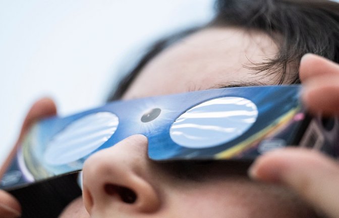 Eine Angestellte eines Fotofachhandelsgeschäft hat eine Sonnenfinsternis-Brille an (gestellte Szene). (zu dpa: «Partielle Sonnenfinsternis hat bei Alaskas Küste begonnen»)<span class='image-autor'>Marijan Murat/dpa</span>