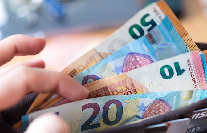 Eine Frau hält eine Geldbörse mit Banknoten in der Hand. Bezieherinnen und Bezieher von Bürgergeld sollen im kommenden Jahr höhere Leistungen erhalten.<span class='image-autor'>Foto: dpa/Monika Skolimowska</span>