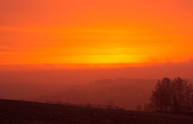 Wegen des Saharastaub in der Luft ist der Himmel bei Sonnenaufgang rötlich gefärbt –  wie hier im sächsischen  Bärenstein. Foto:<span class='image-autor'>Foto: promovie/dpa/Oliver Kaufmann</span>